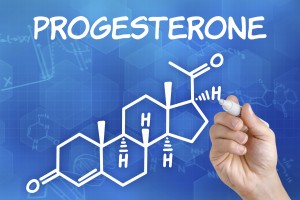Hand with pen drawing the chemical formula of progesterone