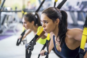 Fitness trx suspension straps training exercises women doing push-ups, working with own weith at gym.