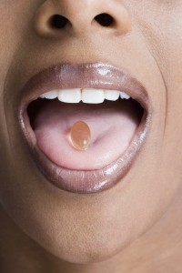 African American woman with vitamin in mouth